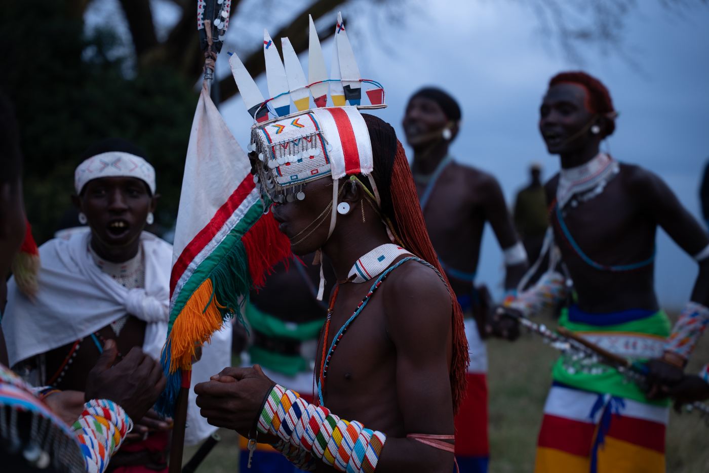 Warriors in ceremonial beadwork dancing at dusk
